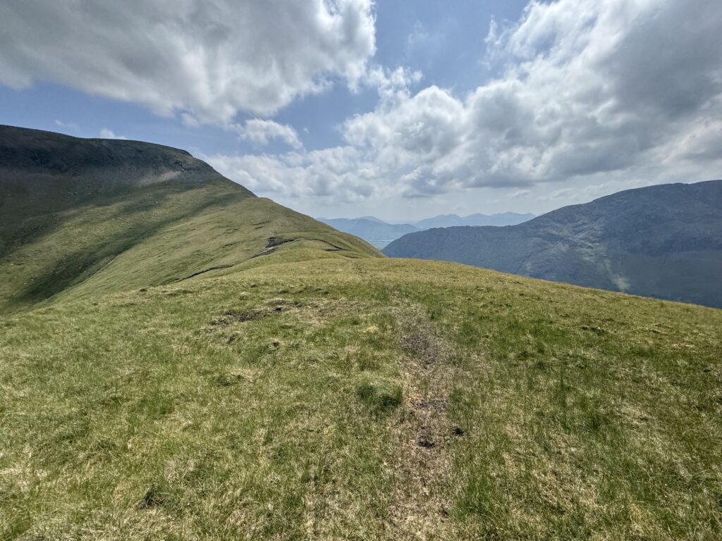 Open grassy ridge with distant peaks and cloud cover, showing scenic views in County Mayo.