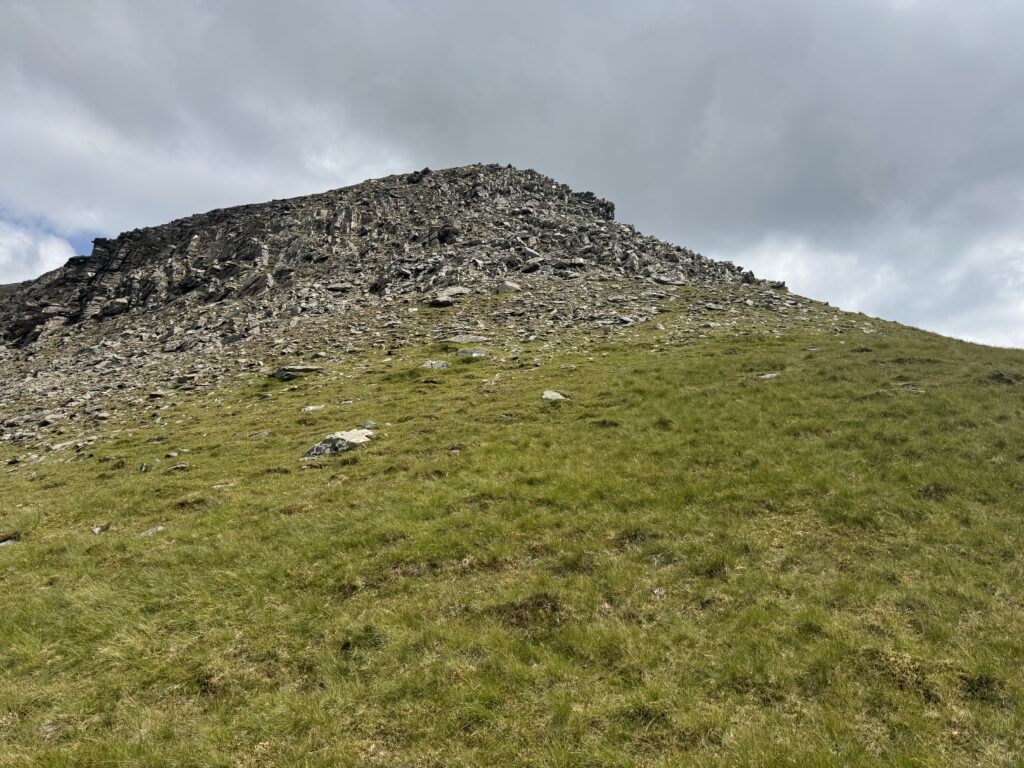 Steep rocky slope near the summit ridge encountered while climbing Barrclashcame, with overcast skies above rugged terrain.