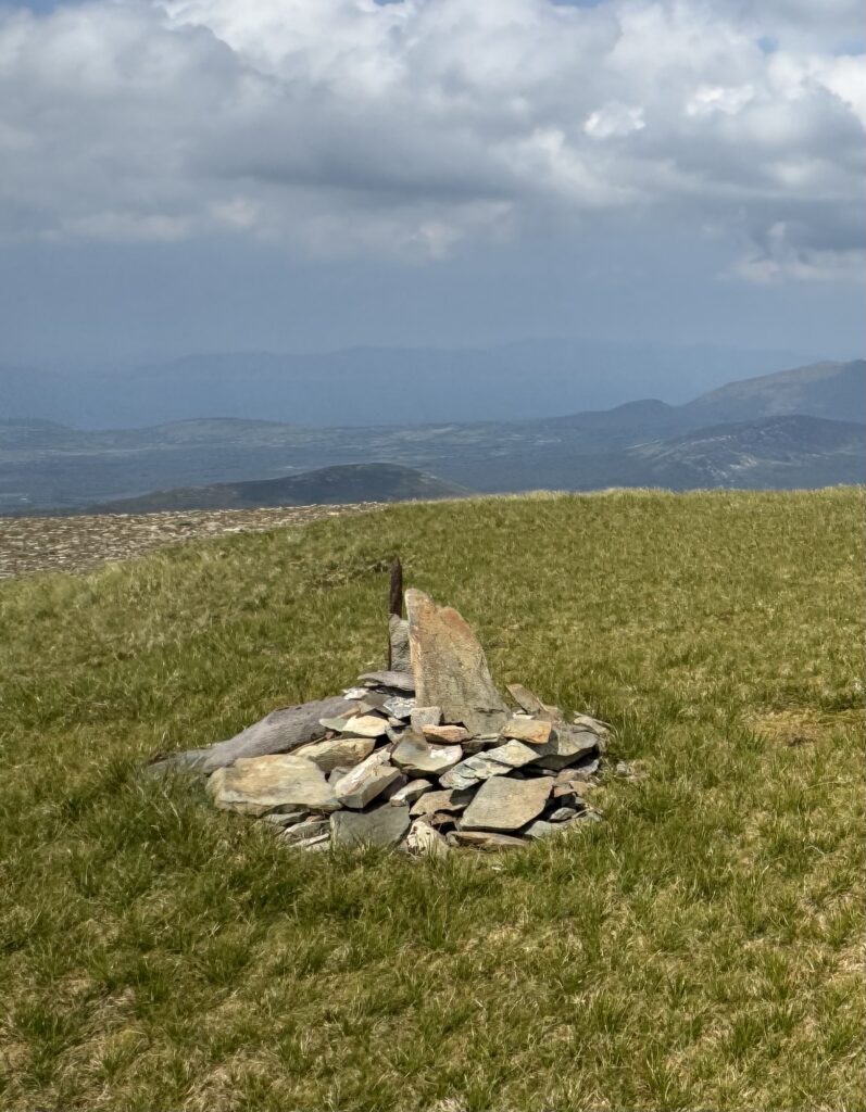 Stone cairn marking the summit of Barrclashcame, captured during a hike in Mayo with distant mountain views in the background.