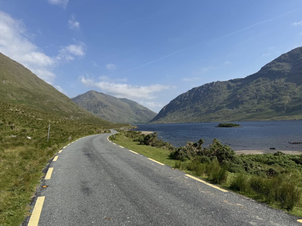 Scenic lakeside road beside Doolough with surrounding peaks near the starting point for climbing Barrclashcame in County Mayo.