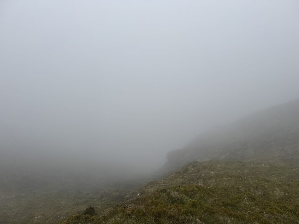 An abyss of cloud beyond a cliff edge.