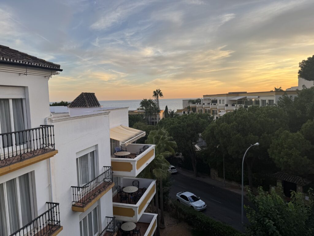 A view from an apartment balcony during a week in Elviria with a 3 year old. The sea shimmers in the distance with the sun setting to the right.