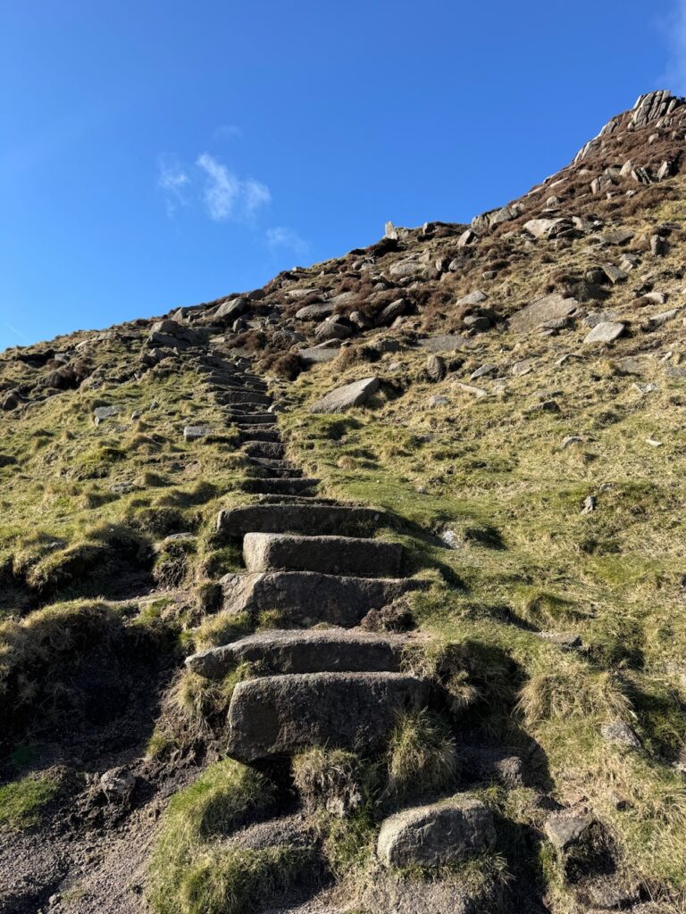Stone steps climbing towards Slieve Bearnagh North Tor after crossing the Mourne Wall.