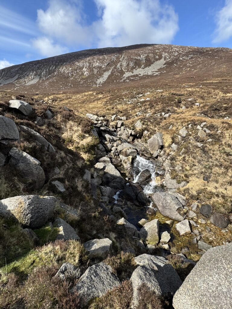Mountain stream flowing through the exposed granite of the Bearnagh Slabs in the Mourne Mountains