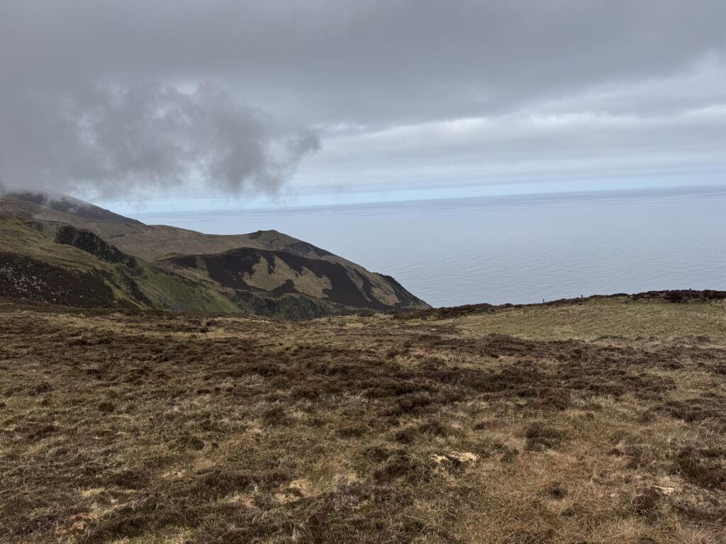 Coastal mountain scenery on the Masatiompan and Sauce Creek walk, with low clouds hanging over the slopes and the Atlantic Ocean beyond