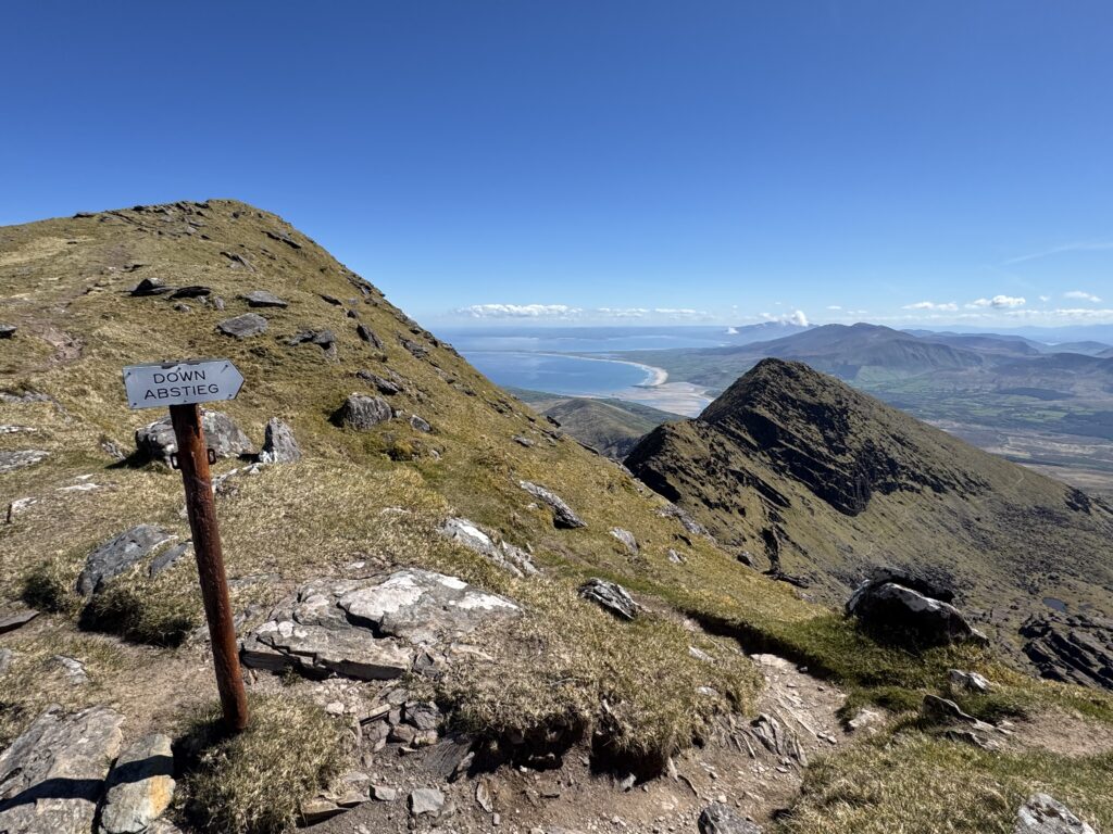Mountain trail sign above Faha Ridge with sweeping views towards Brandon Bay and the Atlantic.