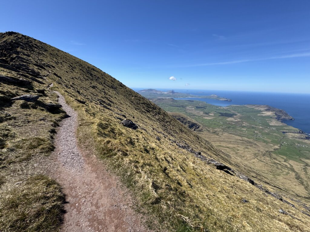 Narrow mountain path high above the Dingle Peninsula with expansive views towards the Atlantic coast.