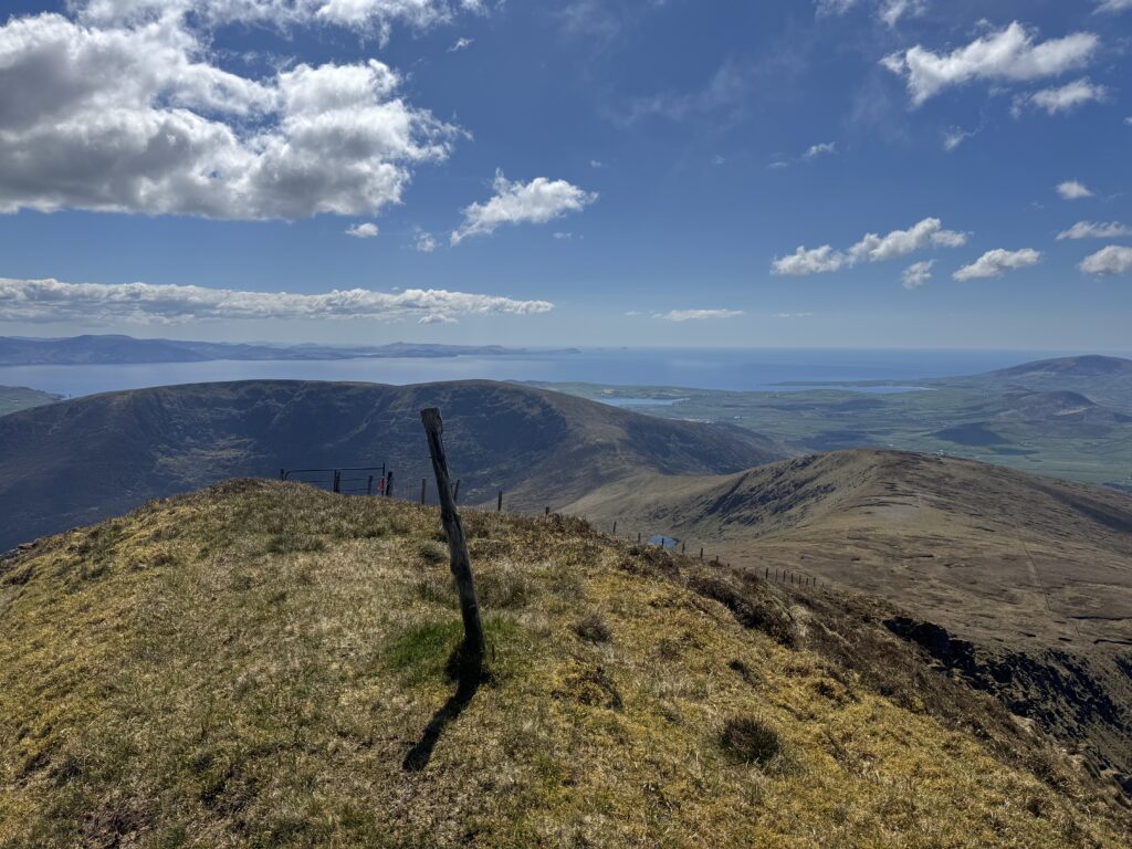 Mountain fence line leading down towards the Dingle Peninsula, with expansive coastal and Atlantic views in the distance.