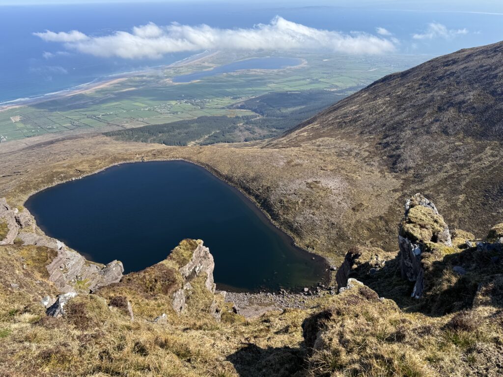 Spectacular views from Beenoskee, one of the best walks in Dingle, overlooking the deep blue waters of Lough Acummeen, steep mountain slopes and the distant beaches and coastline of Brandon Bay.