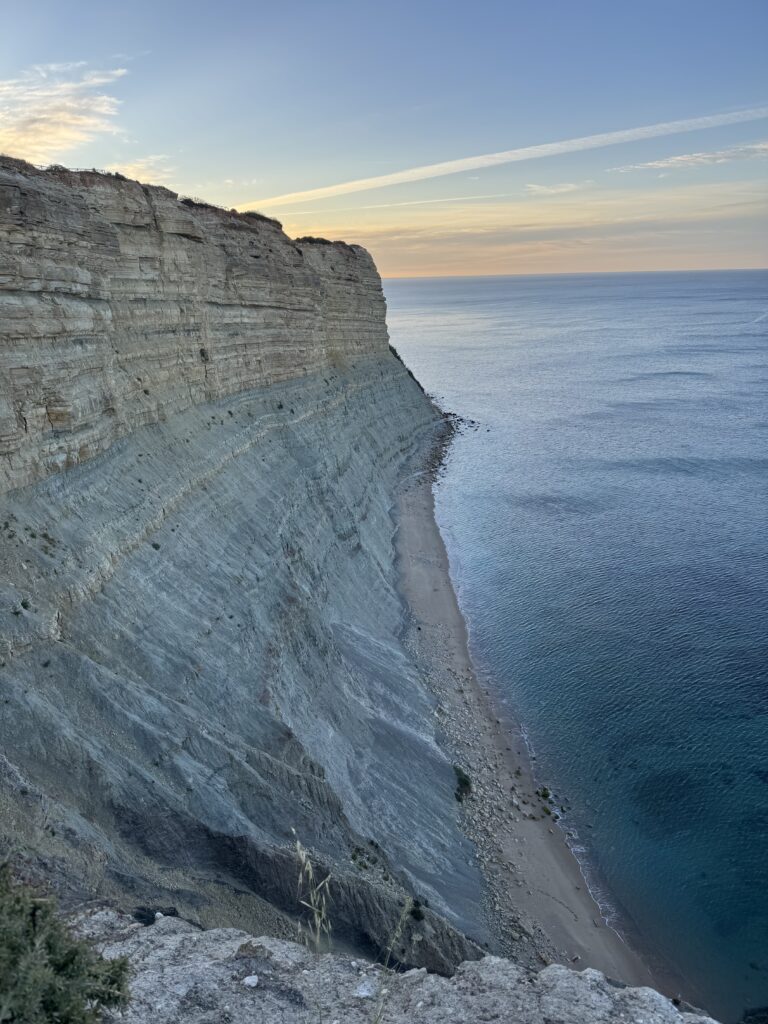 Dramatic limestone cliffs towering above a narrow, secluded beach and the calm Atlantic Ocean near Praia da Luz, photographed during our week in the Algarve with a 3 year old.